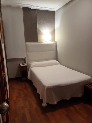 a small bedroom with a white bed with a light on it at Hotel Verdemar in Ribadesella