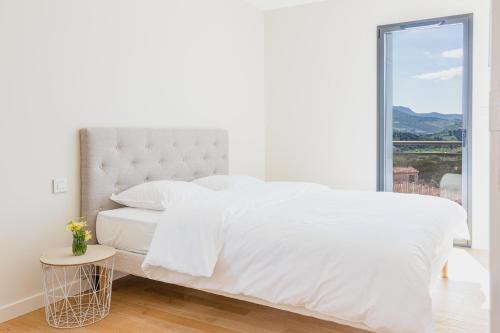 a white bedroom with a white bed and a window at Regina's Banyuls - Modern and brand new apartment in Banyuls-sur-Mer