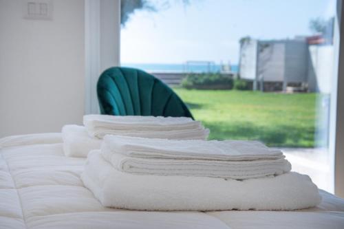 テッラチーナにあるVilla degli Squali Suite Homeのベッド(緑の椅子付)にタオルを積み重ねます。