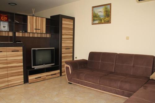a living room with a brown couch and a tv at Ivtour Apartments in Yalta complex in Golden Sands