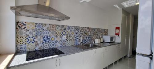 a kitchen with a sink and a tile wall at Rosa D'Aveiro in Aveiro