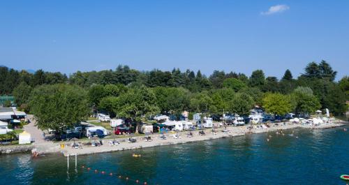 a group of people sitting on a beach next to the water at Camping Solcio in Lesa