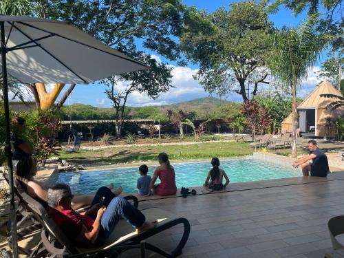 a group of people sitting around a swimming pool at Pyramid Tamarindo Luxury Hotel in Tamarindo