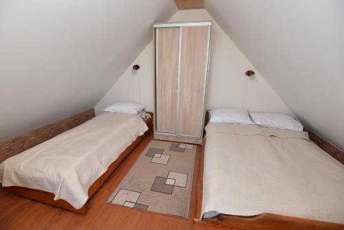 2 łóżka w niewielkim pokoju na poddaszu z szafą w obiekcie Vasarnamis Preiloje pas Žilviną w mieście Neringa