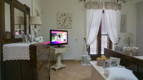 a living room with a television on a dresser with a clock at La stanza della nonna in Modica