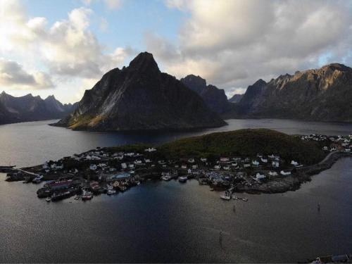 a small island in a body of water with mountains at Madelhea Cabin- Seaview Lodge in Reine