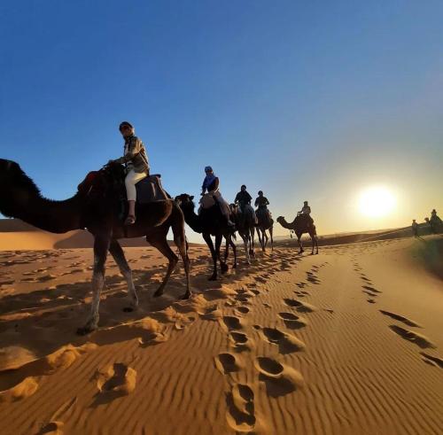 a group of people riding horses in the desert at Sunset luxury camp in Hassilabied