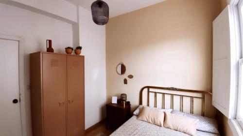1 dormitorio con 1 cama, armario y ventana en Casco antiguo con patio y a 5 min de la playa, en Baiona