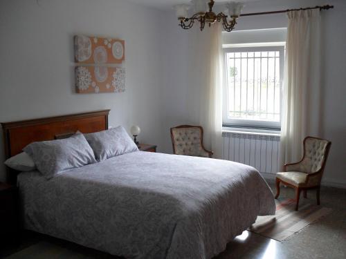 um quarto com uma cama, 2 cadeiras e uma janela em ACAO Vivienda Uso Turístico ARRIBES del Duero em Moral de Sayago