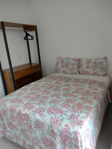 a bed with a floral comforter and a night stand at Casa encantadora com piscina prainha e SPA in João Pessoa