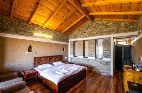 a bedroom with a large bed and a stone wall at Meraki Huts in Pauri
