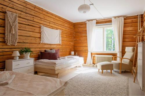 1 dormitorio con paredes de madera, 1 cama y 1 silla en Olo Center by Kolovesi Nature Park, en Enonkoski