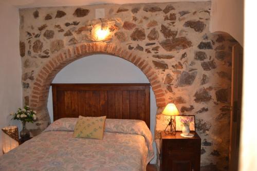 sypialnia z łóżkiem i kamienną ścianą w obiekcie Nidal del Búho Casa Rural w mieście Azuel