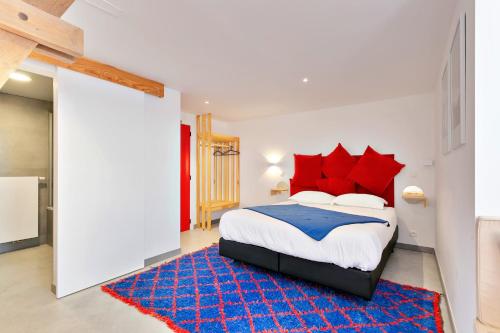 una camera da letto con un letto con cuscini rossi e un tappeto blu di Ô Macra B&B - Aubel, Pays de Herve ad Aubel