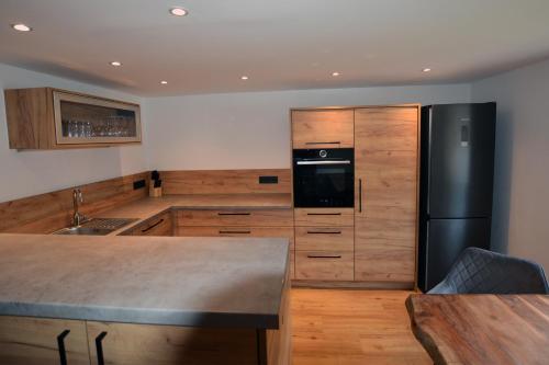 a kitchen with a black refrigerator and wooden cabinets at Gästehaus Lina in Thiersee