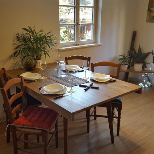une table en bois avec des assiettes et des verres à vin dessus dans l'établissement Maison à colombage La Houblonnière, à Oberbetschdorf