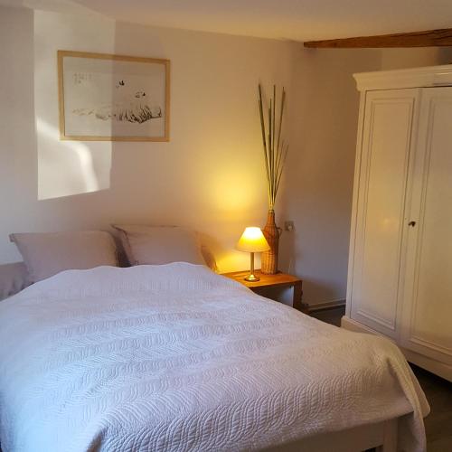 une chambre avec un lit blanc et une lampe dans l'établissement Maison à colombage La Houblonnière, à Oberbetschdorf