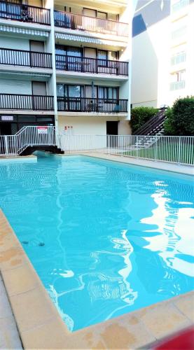 a swimming pool in front of a building at Appartement refait à neuf résidence avec piscine Trouville sur mer in Trouville-sur-Mer