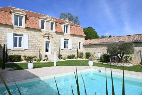 une maison avec une piscine devant une maison dans l'établissement Domaine de Daspe, à Beaupuy