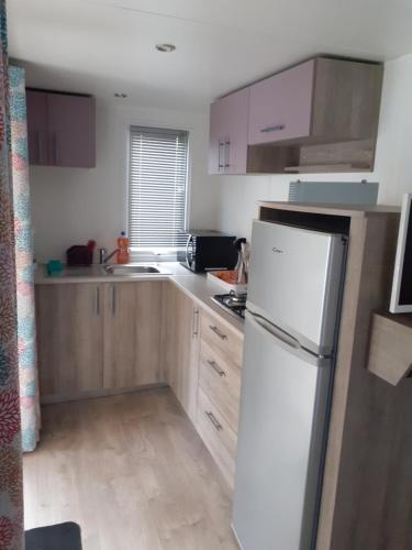 a kitchen with a white refrigerator and wooden cabinets at Mobil-Home/Bungalow in Le Perrier