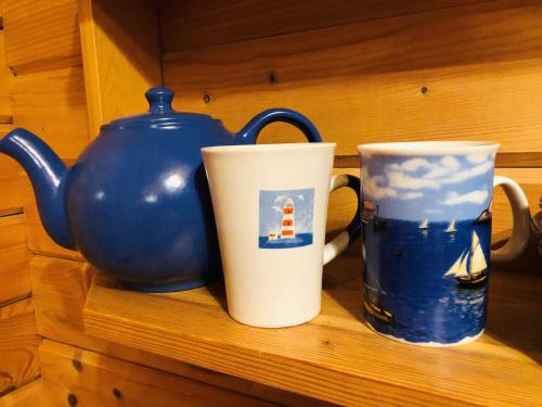 two cups sitting on a shelf next to a blue vase at Merejussi Puhkemajad in Pärna