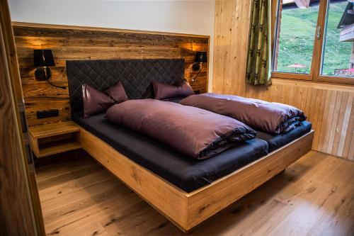 a bed in a wooden room with pillows on it at Gästehaus Oben am Berg in Balderschwang