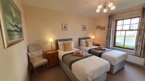 a bedroom with two beds and a window at Roseford Apartment in Crail