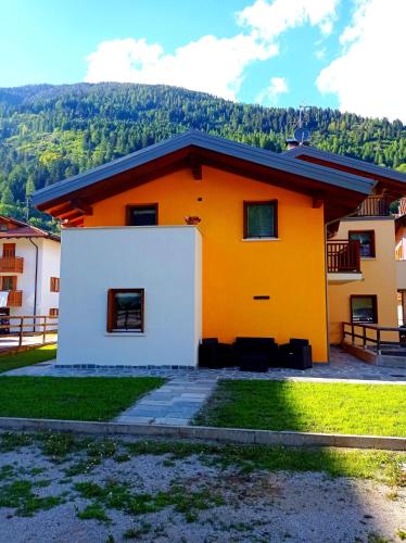 an orange and white house with a mountain in the background at Casa Vacanze Martinelli in Pellizzano