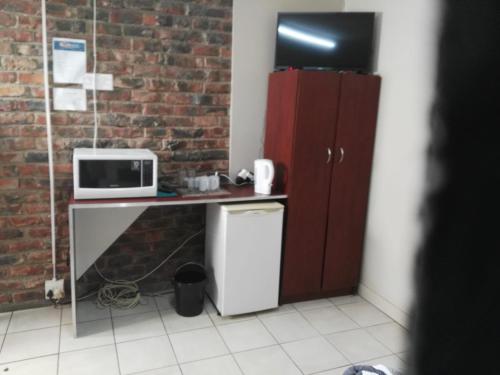 a small kitchen with a microwave and a refrigerator at Ay Jay's Guesthouse in Bloemfontein