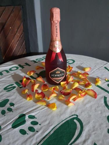 a bottle of champagne on a table with fallen flowers at Ay Jay's Guesthouse in Bloemfontein