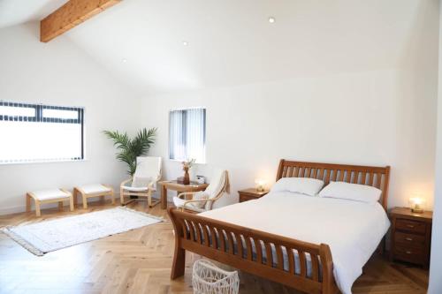 a bedroom with a bed and chairs and a window at Mortham in St Merryn