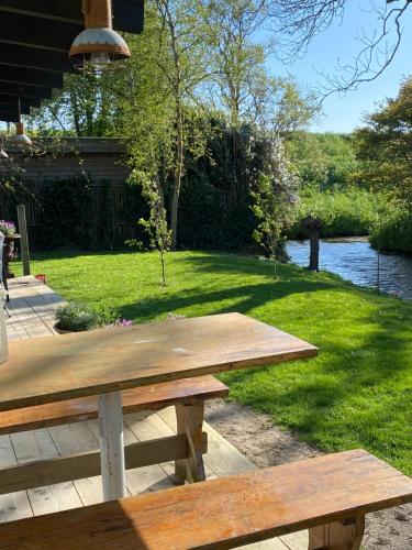 a picnic table in the grass next to a river at Holidayhome Geuzenhoeve op de Munnickaij in Schellinkhout