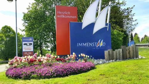 una señal para el anuncio de imiss en un parque con flores en Fewo Saur, en Immenstaad am Bodensee