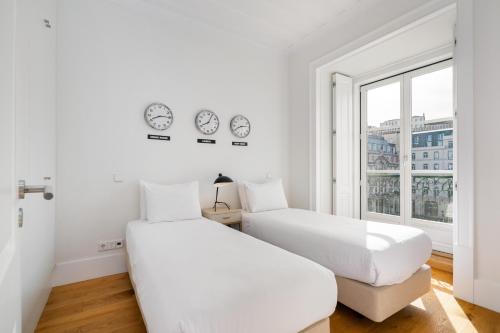 twee bedden in een witte kamer met klokken aan de muur bij WHome Restauradores Deluxe w/ Elevator & AC perfect for Families & Friends in Lissabon
