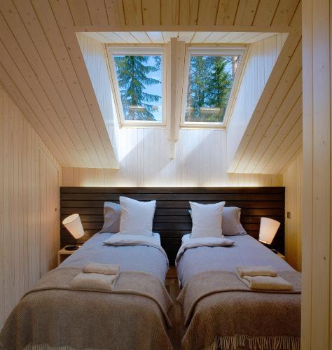 two beds in a room with two windows at Saimaanranta Resort by Anttolanhovi in Mikkeli