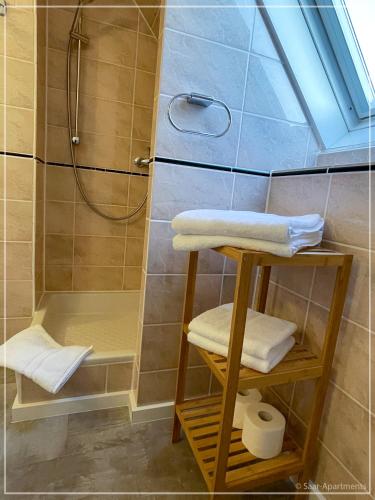 a bathroom with a shower with towels and a sink at Saar-Apartments in Merzig