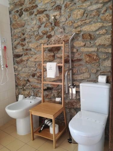 a bathroom with a white toilet and a stone wall at Puial de l Douro in Miranda do Douro