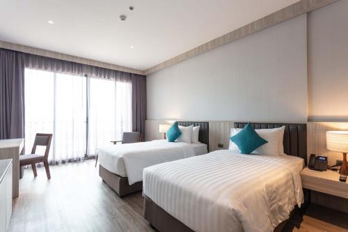 a hotel room with two beds and a desk at Laguna Grand Hotel & Spa Songkhla in Songkhla