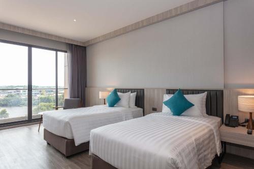 a hotel room with two beds and a large window at Laguna Grand Hotel & Spa Songkhla in Songkhla