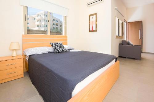 a bedroom with a bed and a chair and a window at Bowker Apartment in Protaras