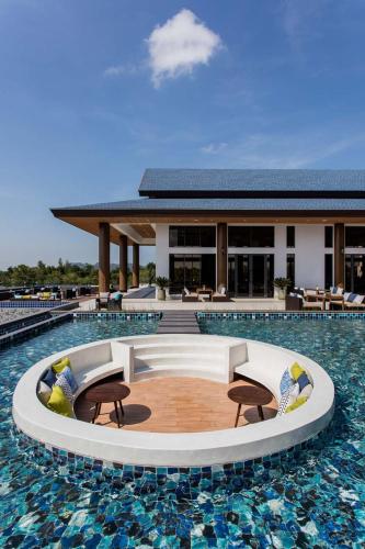 a swimming pool with chairs and a building at Laguna Grand Hotel & Spa Songkhla in Songkhla