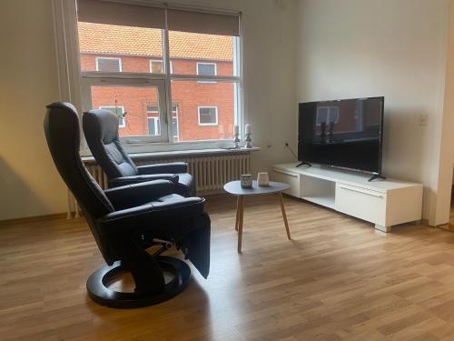 a living room with a chair and a flat screen tv at Grønnegade - tæt på centrum in Esbjerg