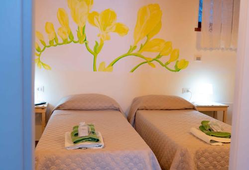 a room with two beds with yellow flowers on the wall at NOVECENTO b&b in Papasidero