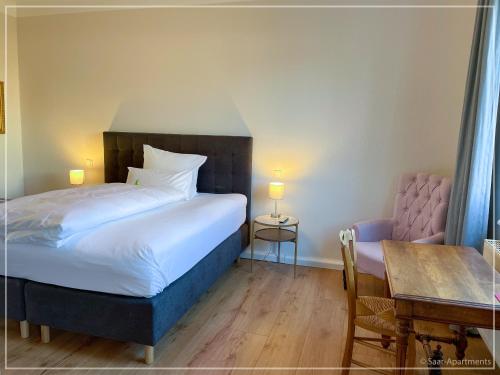 a bedroom with a bed and a table and a table and chair at Saar-Apartments in Merzig