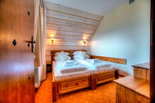 a bedroom with a large bed with wooden walls at Hotel Carpatia Bieszczadzki Gościniec in Wetlina