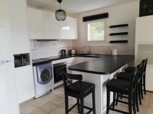 a kitchen with white cabinets and a black counter top at Les calanques in Cavalaire-sur-Mer