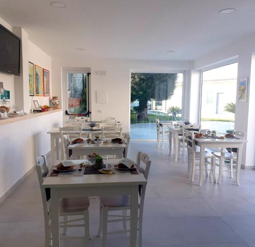 a dining room with white tables and chairs and windows at B & b Venere in Paestum