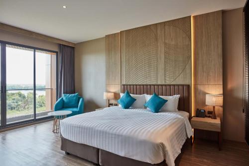 a bedroom with a large bed and a blue chair at Laguna Grand Hotel & Spa Songkhla in Songkhla
