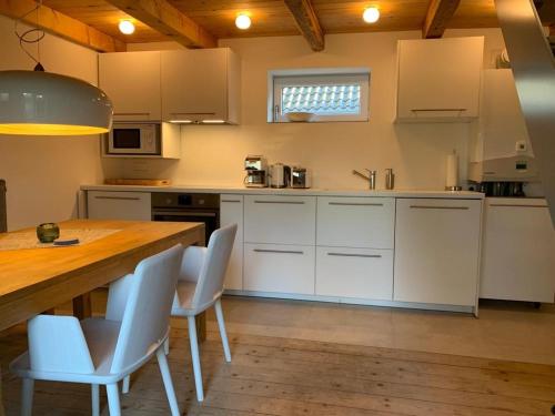 a kitchen with white cabinets and a wooden table at Ferienhaus Peerhus in Katingsiel zwischen Tönning und St Peter Ording in Katingsiel