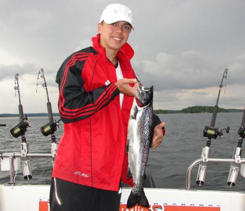 a man holding a fish on a boat at Saimaanranta Resort by Anttolanhovi in Mikkeli